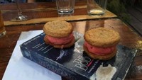 Dua potong cookies isi cream strawberry ini disajikan di atas buku tebal yang sudah tampak tua. Bagian sampul buku bahkan sudah terkelupas. Duh kebayang berapa juta bakteri yang sudah menempel pada makanan ini. Foto: istimewa