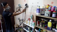 Bekerja siap dengan alat semprot untuk mewarnai sepeda.
