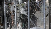 Seorang warga menghancurkan sebuah kaca papan iklan di Kota Mexico, Meksiko, Senin (8/6) waktu setempat.