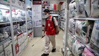 Petugas menyemprotkan cairan disinfektan ke berbagai sudut toko guna mencegah penyebaran virus Corona.