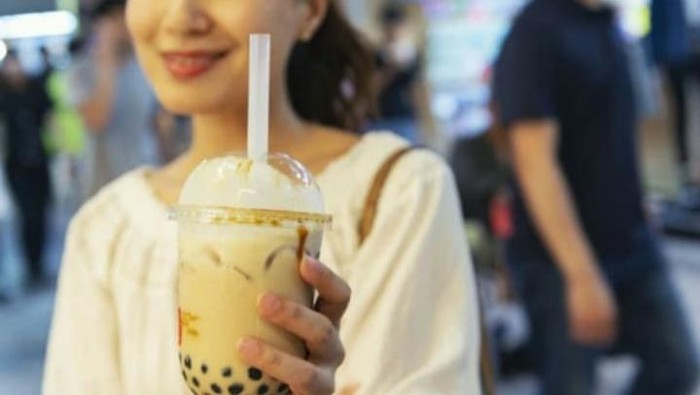 Popular Taiwan drink - Bubble milk tea with tapioca pearl ball in drinking glass on marble white table wooden tray background, close up, copy space