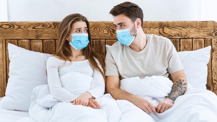 pasutri pakai masker saat bercinta Young male and female in blue protective masks taking photo by phone on tripod at home