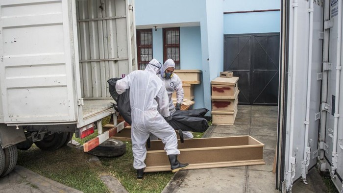 Workers carry a bag with the body of a COVID-19 victim out of a refrigerated container before its cremation at the El Angel crematorium, in Lima on May 21, 2020 - Peru has become the second Latin American country after Brazil to reach 100,000 coronavirus cases, according to health ministry figures out Wednesday. (Photo by Ernesto BENAVIDES / AFP)
