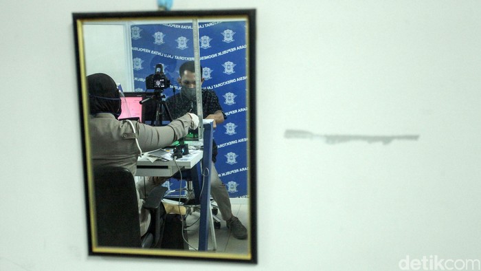 Seorang petugas tengah melayani warga yang ingin mengurus Surat Ijin Mengemudi (SIM) di Satpas Daan Mogot, Jakarta Barat, Rabu (10/6/2020). Saat pandemi Corona ini, pelayanan pembuatan SIM di Satpas menerapkan protokol kesehatan.