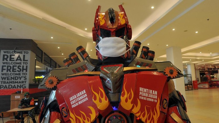 Replika robot transformer menggunakan masker dan memasang imbauan jaga jarak di Transmart Padang, Sumatera Barat, Selasa (9/6/2020). Mall terbesar di Padang itu menerapkan protokol kesehatan mencegah penyebaran COVID-19 yakni dengan menyediakan tempat cuci tangan, pemeriksaan suhu tubuh, penggunaan pelindung wajah dan sarung tangan bagi pekerja, serta melarang pengunjung yang tidak memakai masker untuk masuk. ANTARA FOTO/Iggoy el Fitra/hp.