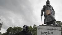 Seorang demonstran berdiri di depan patung mantan Perdana Menteri Britania Raya, Winston Churchill yang menjadi sasaran aksi vandalisme saat aksi Black Lives Matter digelar di kawasan London, pada Minggu (7/6) lalu. AP Photo/Frank Augstein.