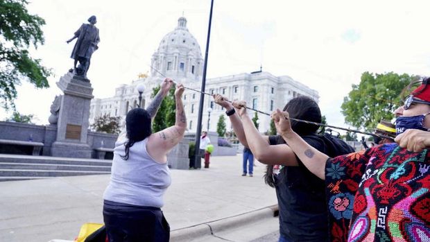 People kick at the head of a Christopher Columbus statue that was torn down at the Minnesota state Capitol in St. Paul, Minn., Wednesday, June 10, 2020. (Evan Frost/Minnesota Public Radio via AP)