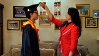 Youna Sompotan (kanan) memindahkan tali toga anaknya yang mengikuti prosesi Wisuda Universitas Sam Ratulangi secara daring dari rumahnya di Manado, Sulawesi Utara, Kamis (11/6/2020).