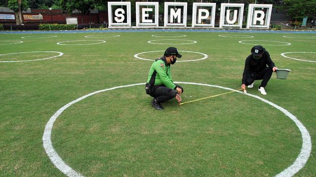 PEMBUATAN JARAK SOSIAL DI TAMAN SEMPUR BOGOR Petugas Park Ranger Kota Bogor mengecat bentuk lingkaran sebagai jarak sosial di lapangan rumput Taman Sempur, Kota Bogor, Jawa Barat, Rabu (10/6/2020). Pengecatan jarak sosial dengan bentuk lingkaran di Taman Sempur itu sebagai salah satu persiapan jelang dibukanya kembali taman tersebut dengan penerapan protokol kesehatan COVID-19 dalam masa transisi Pembatasan Sosial Berskala Besar (PSBB) di wilayah Kota Bogor. ANTARA FOTO/Arif Firmansyah /foc.