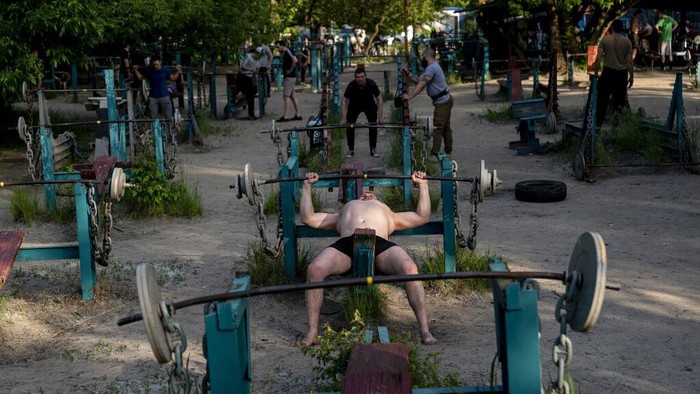 In this photo taken on Sunday, June 7, 2020, a man trains in the outdoors gym on the Dolobetskiy island on the Dnipro River in Kyiv, Ukraine. Relishing an opportunity to do exercise after a long lockdown, hundreds of Kyiv residents flock to an improvised outdoor workout on an island facing the Ukrainian capital. The Kachalka gym on the Dolobetskiy island on the Dnipro river has enjoyed broad popularity ever since it opened in 1966. (AP Photo/Evgeniy Maloletka)