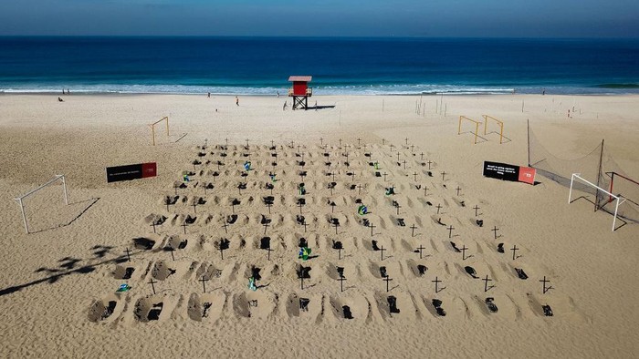 Aksi Kuburan Palsu di Pantai Brasil RIO DE JANEIRO, BRAZIL - JUNE 11: An aerial view of symbolic graves digged by protesters from the NGO 'Rio De Paz' as a sign of protest in Copacabana beach on June 11, 2020 in Rio de Janeiro, Brazil. Volunteers dug 100 shallow graves symbolizing the deaths of coronavirus (COVID-19) in the country. The act calls for transparency and an attitude change from the government to fight the pandemic. (Photo by Buda Mendes/Getty Images)