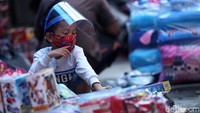 Seorang anak dengan memakai pelindung wajah berbelanja mainan di Pasar Pagi, Jakarta.