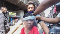 Seorang pembeli yang membawa anaknya memakai face shield.