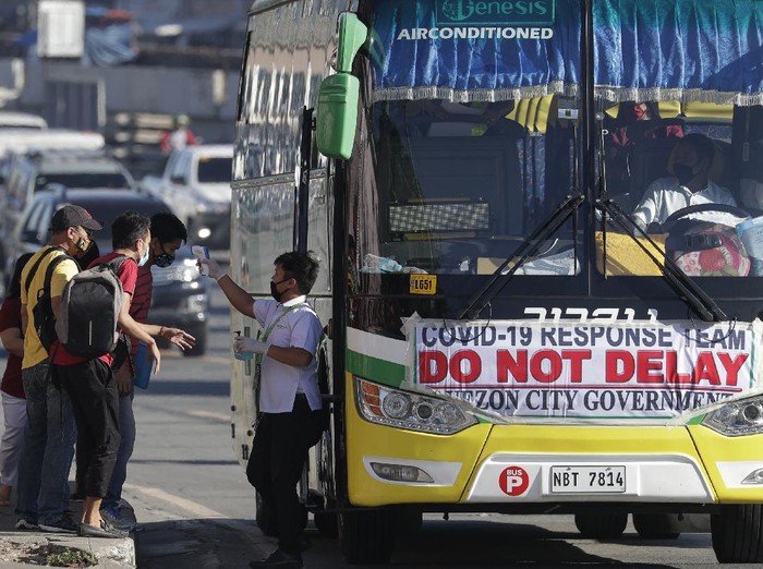 Commuters have their temperature checked before boarding a bus following the easing of the lockdown to prevent the spreading of the new coronavirus in Manila, Philippines Tuesday, June 2, 2020. The Philippine capital has shifted to a more relaxed quarantine with limited public transport in a high-stakes gamble to slowly reopen the economy while fighting the coronavirus outbreak. (AP Photo/Aaron Favila)