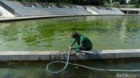 Seorang pekerja membersihkan kolam di sekitar Patung Monumen Pembebasan Irian Barat