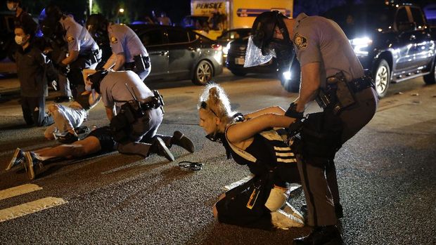 A person is covered with liquid after being officials deployed teargas at protesters Saturday, June 13, 2020, near the Atlanta Wendy's where Rayshard Brooks was shot and killed by police Friday evening following a struggle in the restaurant's drive-thru line in Atlanta. (AP Photo/Brynn Anderson)
