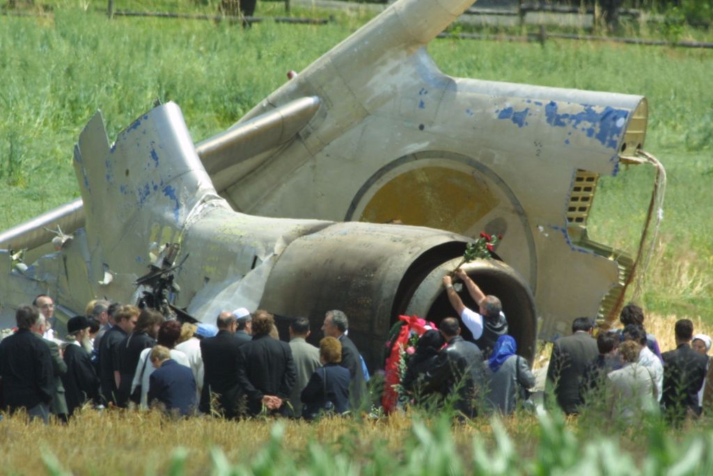 UEBERLINGEN, GERMANY - JULY 4:  A visiting family member of a victim attaches roses to the burned out wreckage of a Bashkirian Airlines Tupolev-154 plane as other Russian family members gather around to pay tribute to their lost loved ones July 4, 2002 near the southern German town of Ueberlingen. The aircaft collided with a DHL express service cargo plane during the night of July 1, 2002 killing 71 people, mostly children and teenagers.  (Photo by Sean Gallup/Getty Images)