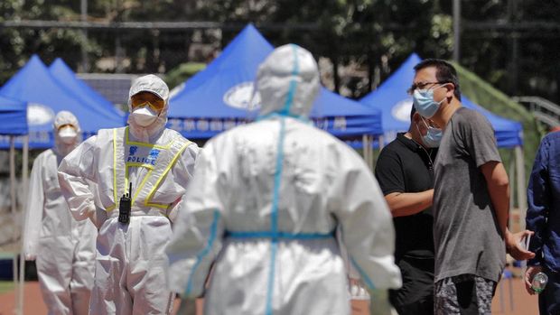 Workers put on protective suits as they wait for people living surrounding the Xinfadi wholesale market arrive to get a nucleic acid test at a stadium in Beijing, Sunday, June 14, 2020. China is reporting its highest daily total of coronavirus cases in two months after the capital's biggest wholesale food market was shut down following a resurgence in local infections. (AP Photo/Andy Wong)