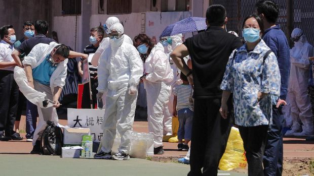 Workers put on protective suits as they wait for people living surrounding the Xinfadi wholesale market arrive to get a nucleic acid test at a stadium in Beijing, Sunday, June 14, 2020. China is reporting its highest daily total of coronavirus cases in two months after the capital's biggest wholesale food market was shut down following a resurgence in local infections. (AP Photo/Andy Wong)