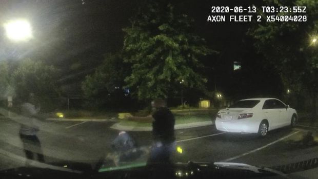 This screen grab taken from dashboard camera video provided by the Atlanta Police Department shows Rayshard Brooks, left, and Officer Garrett Rolfe pointing Tasers at one another, while Officer Devin Brosnan is seen getting up after a struggle among the three men in the parking lot of a Wendy's restaurant, early Saturday, June 13, 2020, in Atlanta. Rolfe has been fired following the fatal shooting of Brooks and Brosnan has been placed on administrative duty. (Atlanta Police Department via AP)