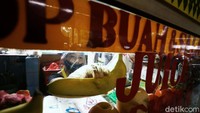  Pedagang memakai masker dan pelindung wajah saat melayani pembeli.