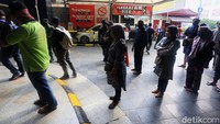 Pengunjung antre masuk pasar dengan menerapkan jaga jarak.
