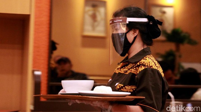 Penerapan protokol kesehatan turut diterapkan di sejumlah rumah makan. Para pramusaji pun diwajibkan pakai masker saat bekerja.