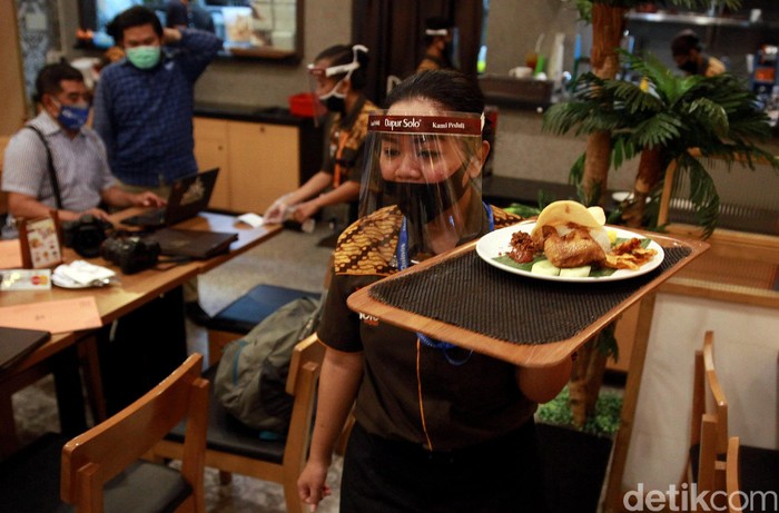 Penerapan protokol kesehatan turut diterapkan di sejumlah rumah makan. Para pramusaji pun diwajibkan pakai masker saat bekerja.