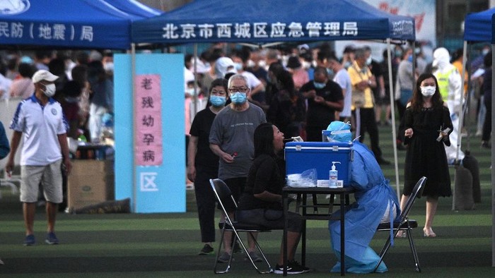 A health worker wearing a protective suit takes a swab test from a woman at Guangan Sport Center for people who visited or live near the Xinfadi Market in Beijing on June 14, 2020. - The domestic COVID-19 coronavirus outbreak in China had been brought largely under control through strict lockdowns that were imposed early this year -- but a new cluster has been linked to Xinfadi market in south Beijing. (Photo by Noel Celis / AFP)