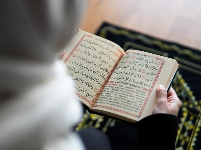 Muslim woman reading from the quran stock photo
