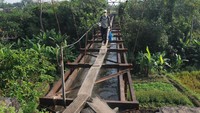 Seorang warga melewati papan kayu yang dipasang pada jembatan irigasi di Ngemplak, Boyolali, Jawa Tengah, Selasa (16/6/2020).