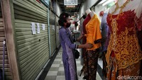 Seorang pedagang merapikan dagangan di depan kiosnya.