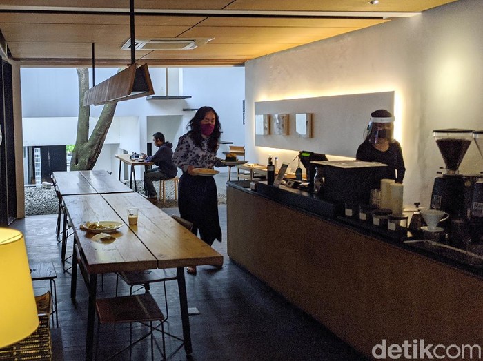 Barista menyajikan menu kopi di coffee shop Kopi Manyar, Bintaro, Jakarta Selatan, Selasa  (16/6/2020).  Coffee shop yang didesain oleh arsitek beken Andra Matin tersebut kembali melayani layanan makan di tempat (dine in) dengan menerapkan tatanan normal baru dengan menjalankan protokol kesehatan guna mencegah penularan COVID-19. Layanan dine in mulai dilakukan sejak Senin (15/6) sesuai aturan PSBB transisi pemerintah.