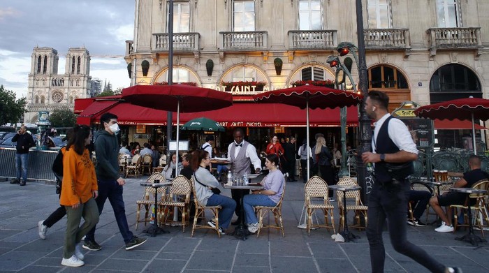People sit on a cafe, Monday, June 15, 2020 in Paris. Paris is rediscovering itself, as its cafes and restaurants reopen for the first time since the fast-spreading virus forced them to close their doors March 14. Restaurants outside the Paris region opened earlier this month, and Paris cafes were allowed to serve people outside but not open their doors. After three months of losses, some restaurateurs fear it will take a long time for business to come back. (AP Photo/Thibault Camus)