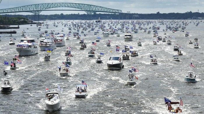 Trump Birthday-Florida Brian Masotti, left, and Tracey Warren wave flags at the hundreds of boats idling on the St. Johns River during a rally Sunday, June 14, 2020, in Jacksonville, Fla., celebrating President Donald Trump's birthday. (Will Dickey/The Florida Times-Union via AP)