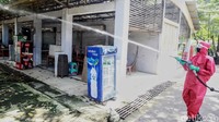 Petugas melakukan penyemprotan dengan memakai APD lengkap.