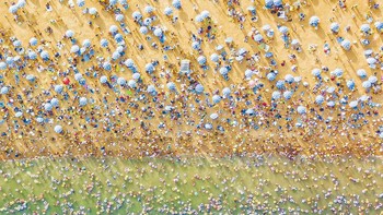 Fotografer Perancis William Markezana mengabadikan pemandangan menakjubkan dari pantai Dameisha yang ramai di Cina. Dia mengatakan ini  adalah pantai umum di sebelah hotel bintang lima. Hotel tersebut memiliki pantai pribadi tepat di sebelahnya, yang kosong.  Foto: Agora via Daily Mail