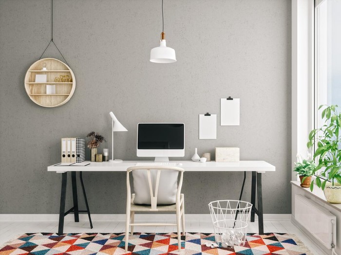 Posters on grey wall above white cupboard in bright living room interior with sofa and carpet. Real photo