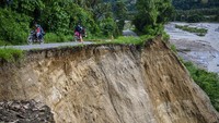 Sejumlah pengendara sepeda motor melintas di jalan yang sebagian ruasnya longsor di Desa Omu, Sigi, Sulawesi Tengah. Longsor terjadi di salah satu ruas jalan yang hampir memutuskan lalu lintas tersebut.
