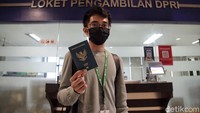 Seorang warga memamerkan paspor yang sudah dibuat.