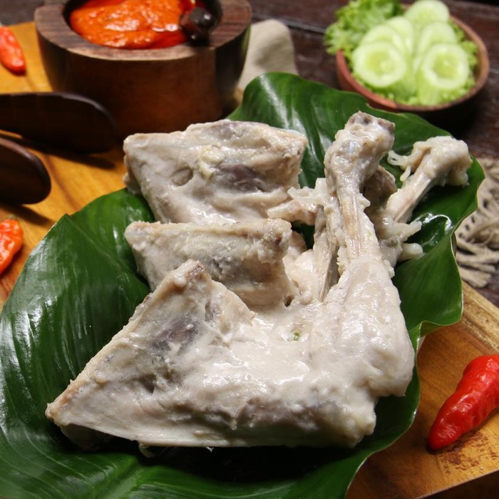 Ilustrasi ayam pop Ayam Pop, a popular chicken dish from Minangkabau, Padang, West Sumatra. The chicken is braised in coconut milk and spices; then only lightly fried. It is served with a special spicy paste of red chili peppers, tomatoes, and broad beans. The chicken pieces are arranged on rectangular wooden serving block that has been lined with a broad green leaf. On the other end is the chili paste. Some chili peppers are scattered on the tray. Some green vegetables of cassava leaves, lettuce and cucumber slices are also served along the chicken dish. A wooden plate with two matching wooden cutleries are placed next to the tray.