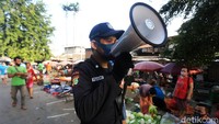 Petugas keamanan berkeliling mengimbau warga dan pedagang untuk jaga jarak dan memakai masker.