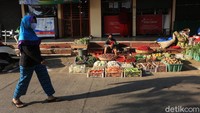 Seorang warga melintas di depan lapak pedagang yang telah menerapkan physical distancing sebagai cara pencegahan penyebaran virus Corona.