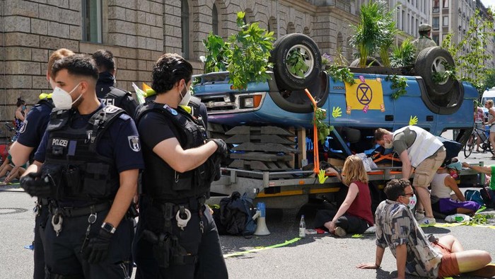 Sejumlah warga gelar demo terkait perubahan iklim di Berlin, Jerman. Sebuah mobil terbalik yang dihiasi dengan sejumlah tumbuhan dan poster ramaikan aksi itu.