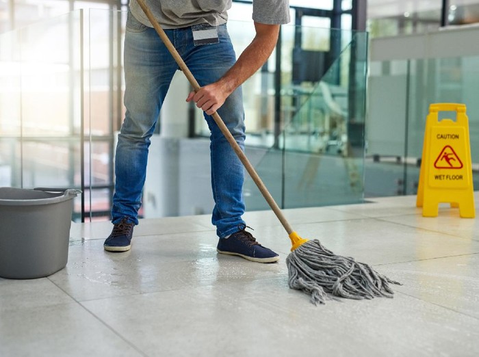 Shot of an unrecognizable man mopping the office floor