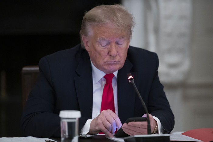President Donald Trump looks at his phone during a roundtable with governors on the reopening of Americas small businesses, in the State Dining Room of the White House, Thursday, June 18, 2020, in Washington. (AP Photo/Alex Brandon)