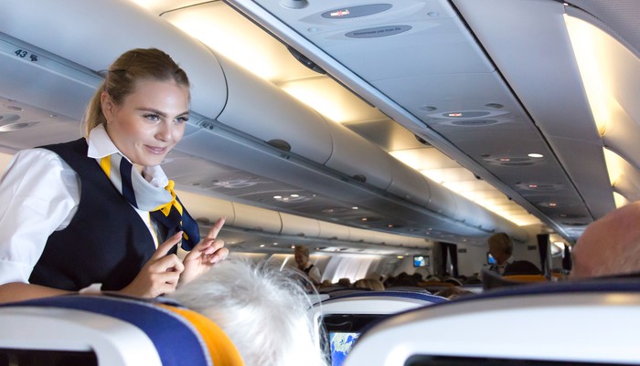 Munich: A female flight attendant  is speaking with a passenger sitting in the economy class of the route Munich - Vancouver of Lufthansa Airlines.