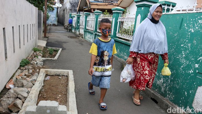 Makam di Jalanan Kelurahan Pisangan Warga melintas di samping kuburan yang berada di akses jalan lingkungan warga daerah Pisangan, Jakarta Timur, Jumat, (19/6/2020). Kuburan yang berada di tengah jalan tersebut saat ini sedang proses untuk pemindahan oleh pihak keluarga dan Kelurahan Pisangan Timur ke TPU Kemiri. Makam itu telah ada sejak 1940-an.