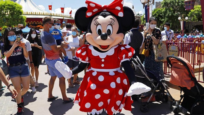 The iconic cartoon character Minnie Mouse waves to visitors at the Hong Kong Disneyland on Thursday, June 18, 2020. Hong Kong Disneyland on Thursday opened its doors to visitors for the first time in nearly five months, at a reduced capacity and with social distancing measures in place. The theme park closed temporarily at the end of January due to the coronavirus outbreak, and is the second Disney-themed park to re-open worldwide, after Shanghai Disneyland. (AP Photo/Kin Cheung)