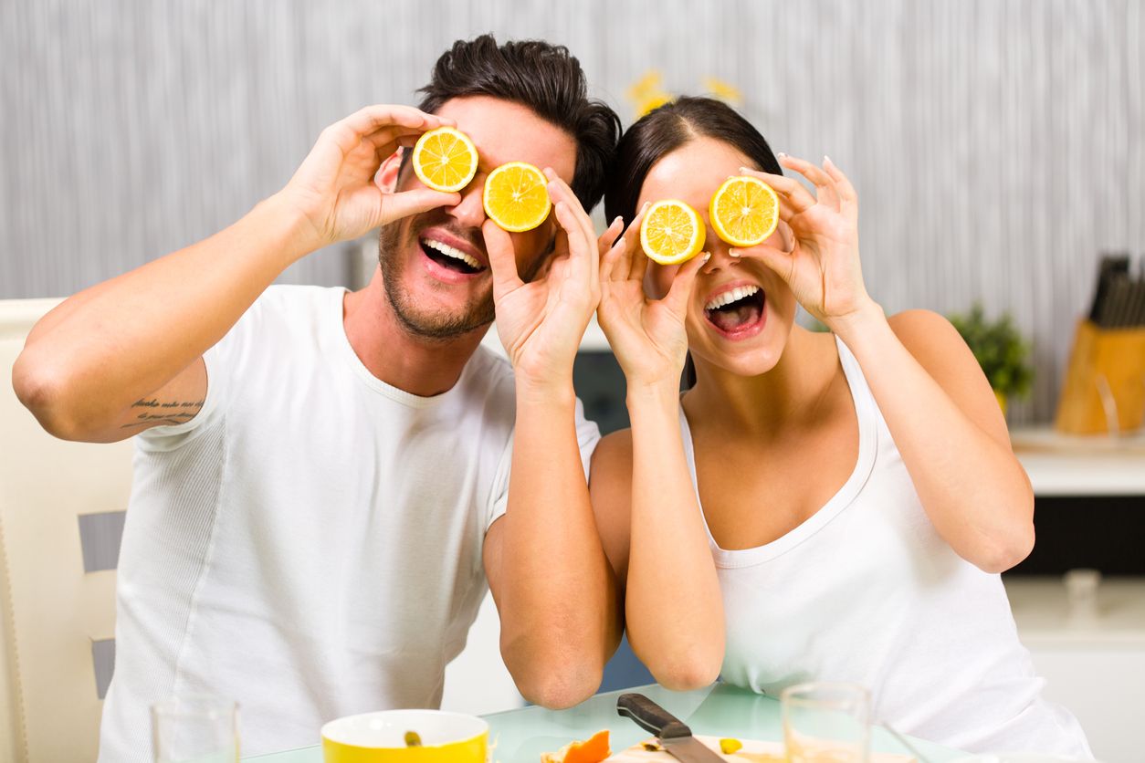Young man and woman having fun with lemon while having a breakfast.
